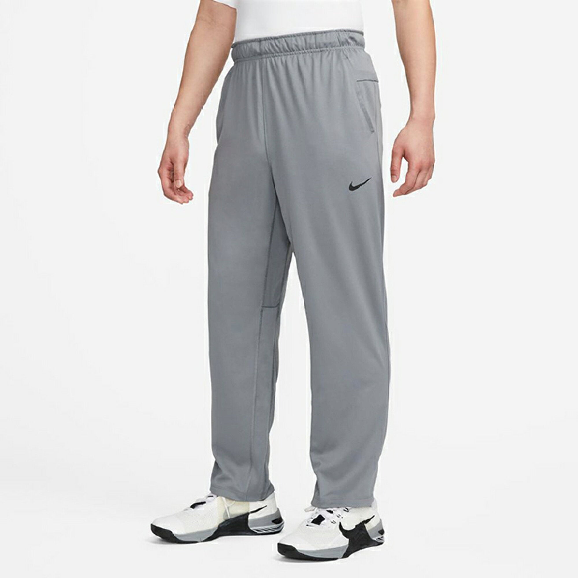 The image shows a man wearing Nike training bottoms with a sleek fit, emphasizing comfort and flexibility.