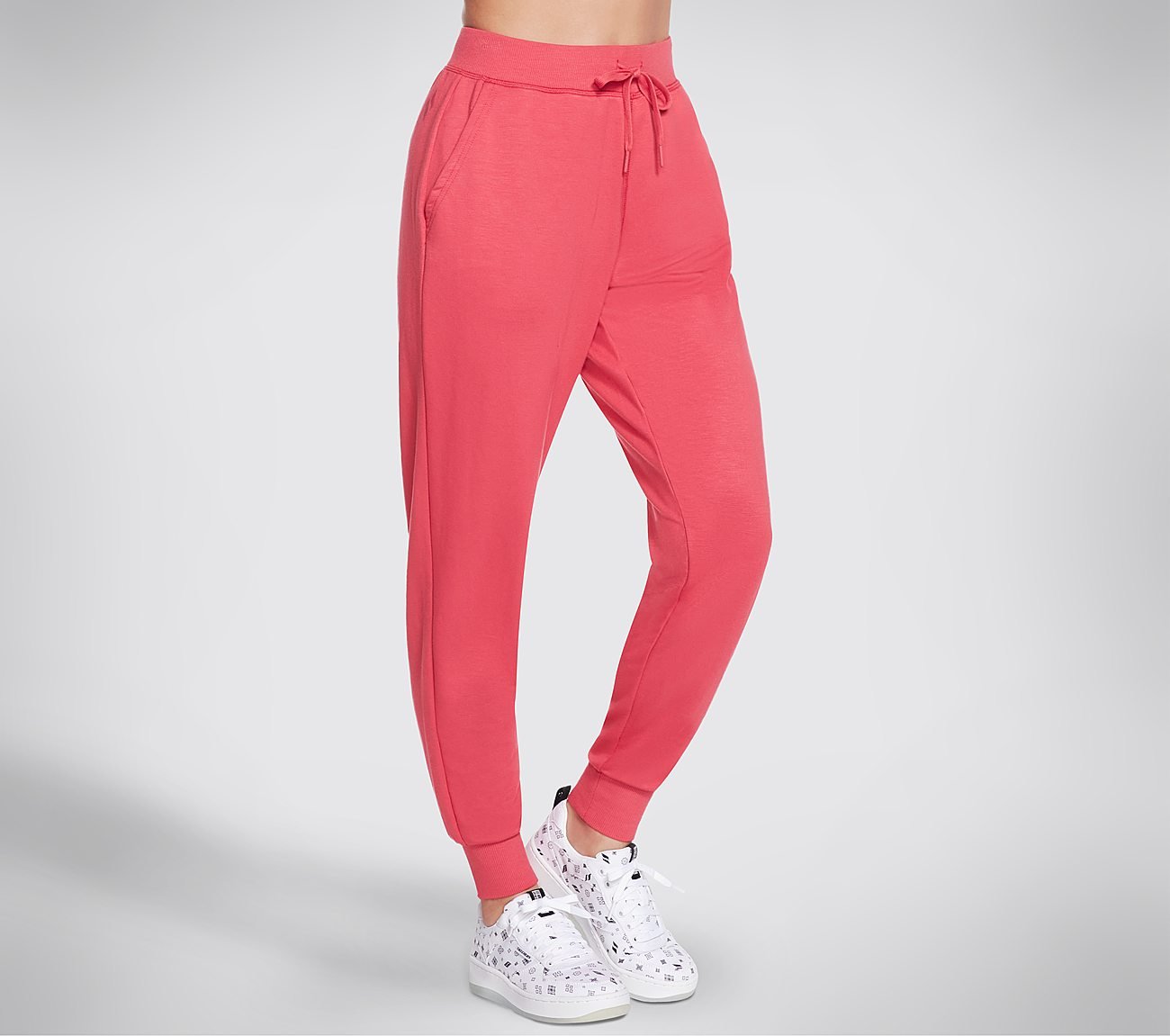 The photo shows a pair of Skechers women’s joggers laid flat to showcase the slim-fit design, elastic waistband, and soft, high-quality fabric. The angle highlights the stitching and sleek cut