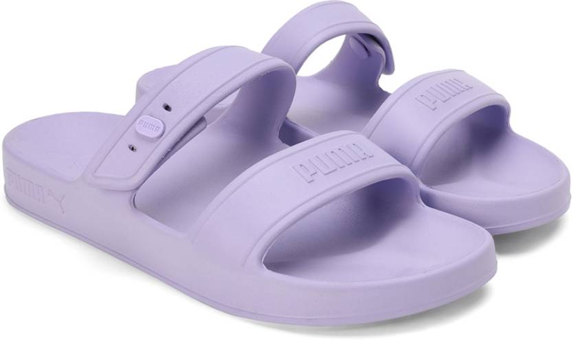 A top-down view of PUMA slippers for women, highlighting their soft, cushioned sole and sleek design. The slippers are displayed with the PUMA logo visible, placed on a clean, neutral background to emphasize their comfort and style.